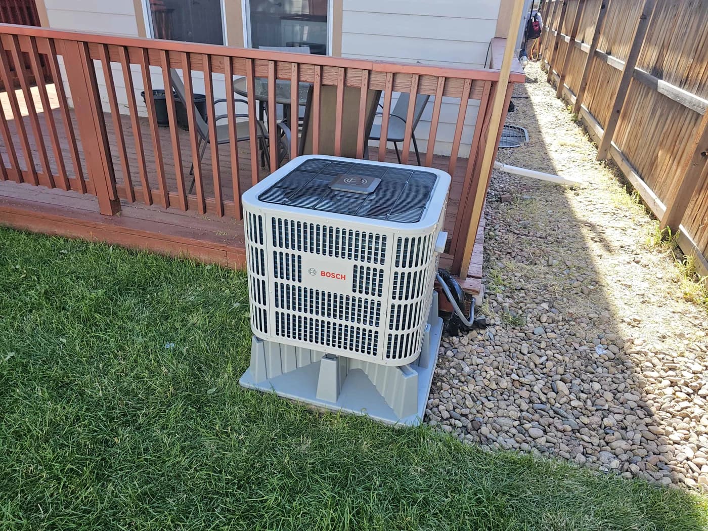 Bosch heat pump on a raised base beside a red wooden deck