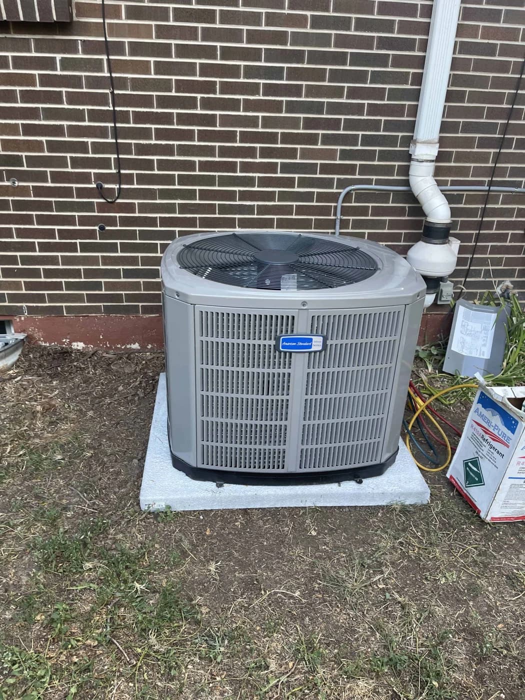 American Standard outdoor unit installed beside a red brick house