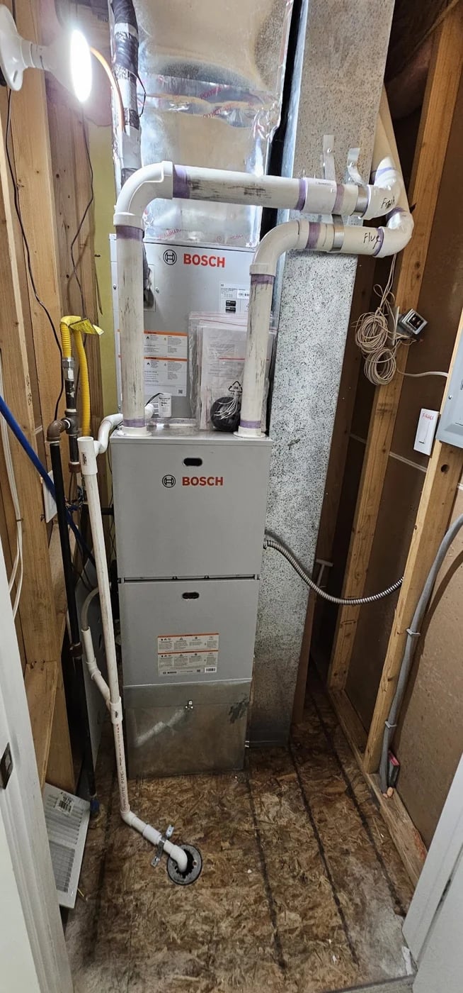 A Bosch furnace in a tight basement bay under the supply plenum and white PVC venting